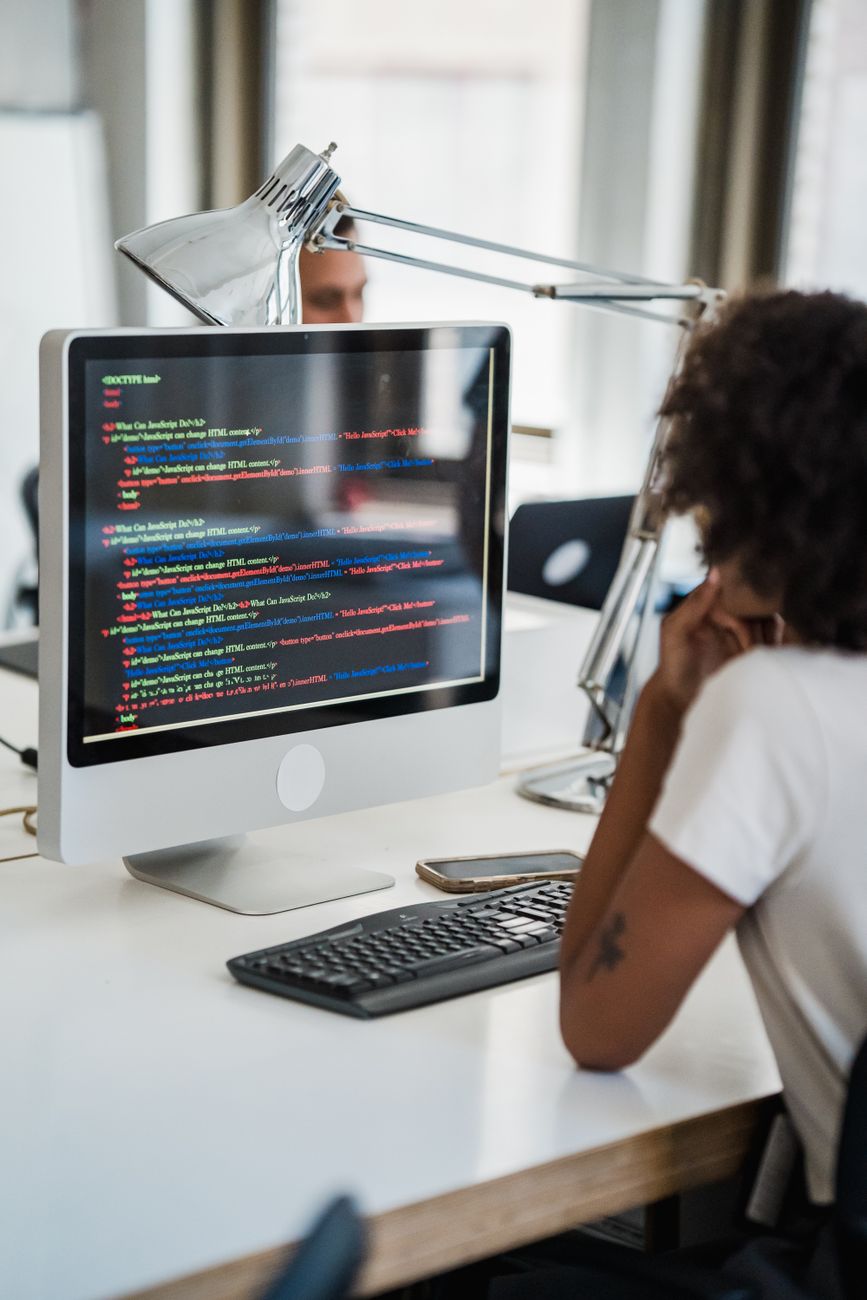 A young coder writing software on multiple screens in a contemporary office space